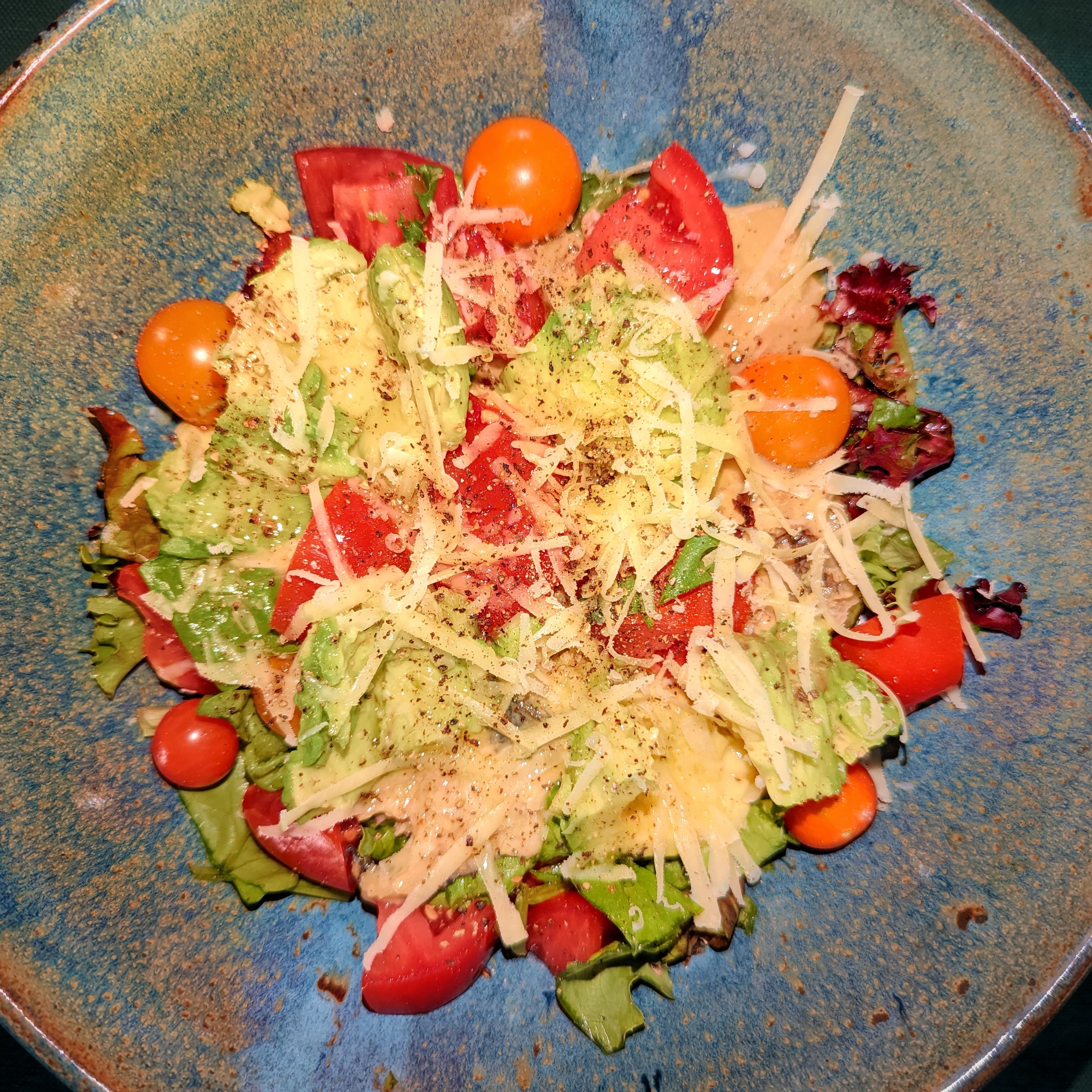 Mixed green salad with tomatoes, avocado, cheddar, and dressing for lunch recipes